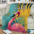 Bright pink flamingo blanket styled across a sofa with teal and gold foliage