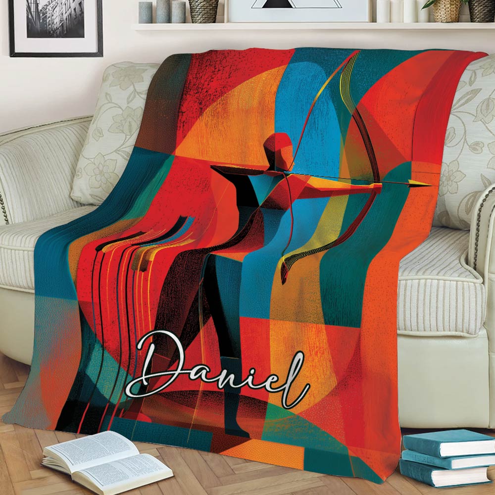 Geometric archer throw blanket displayed across a sofa with bold red, teal, orange and yellow artwork