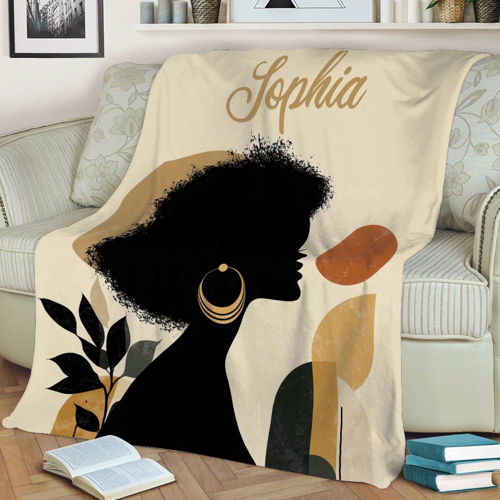 Living room display of an African-inspired blanket with Black woman silhouette, botanical details, and neutral tones