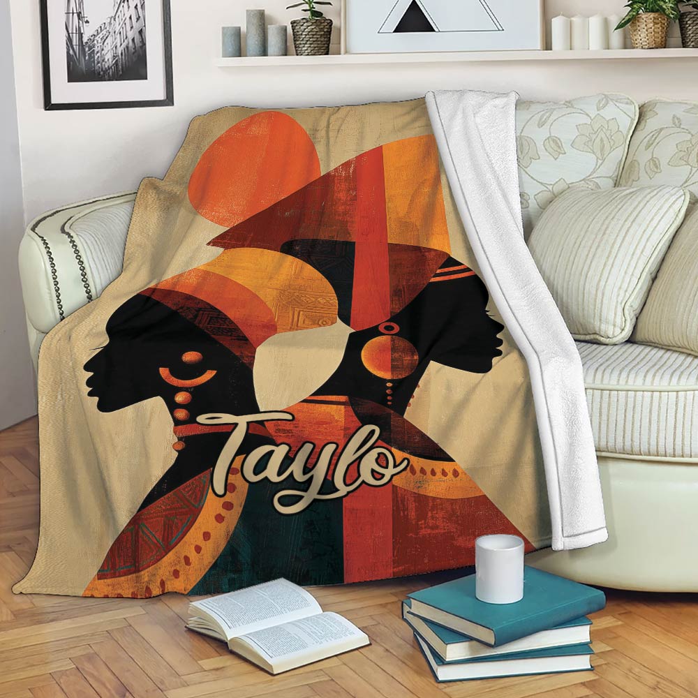 African-inspired throw blanket displayed on a sofa with bold female silhouettes and geometric cultural artwork