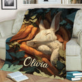 Rabbit blanket displayed on a sofa with a peaceful white bunny surrounded by carrots and botanical leaves