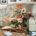Open-book and flower artwork on a throw blanket styled in a cozy reading space