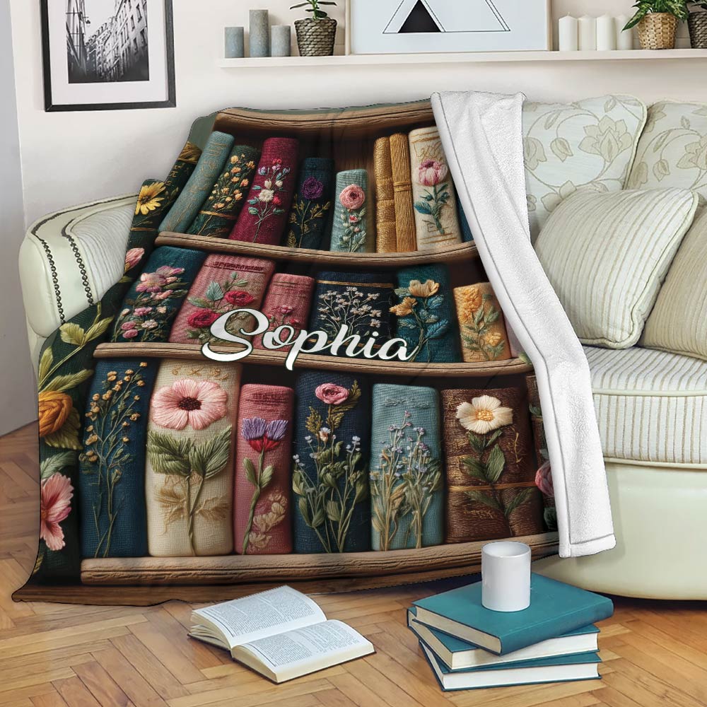 Book lover throw blanket displayed on a sofa with open books and floral bookshelf artwork