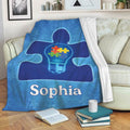 Autism awareness throw blanket displayed on a sofa with blue puzzle artwork and colorful pieces