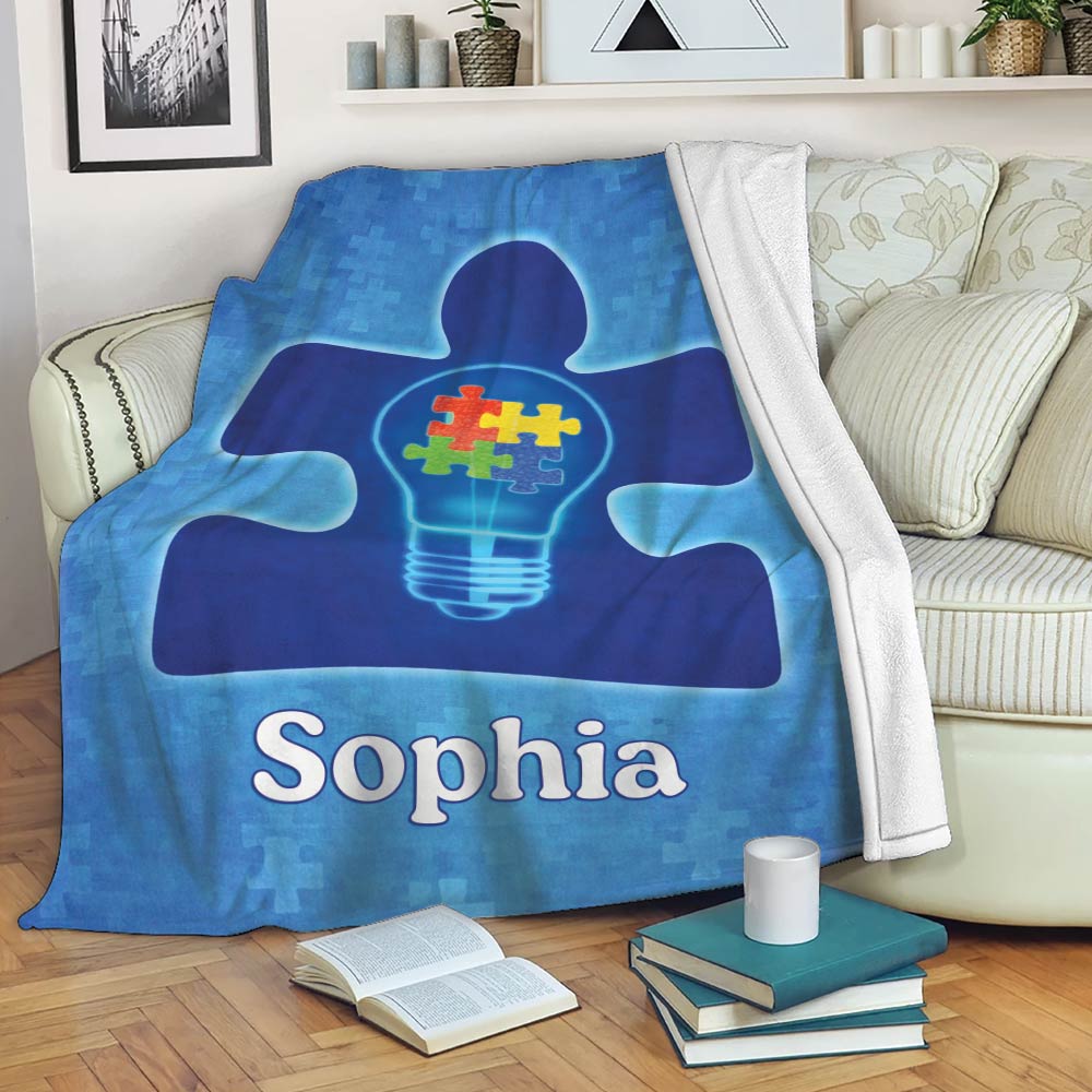 Autism awareness throw blanket displayed on a sofa with blue puzzle artwork and colorful pieces