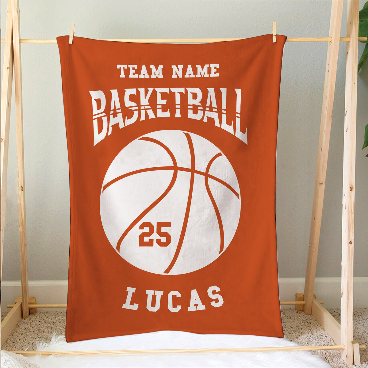 Orange basketball blanket displayed on a wooden frame with varsity-style sports artwork