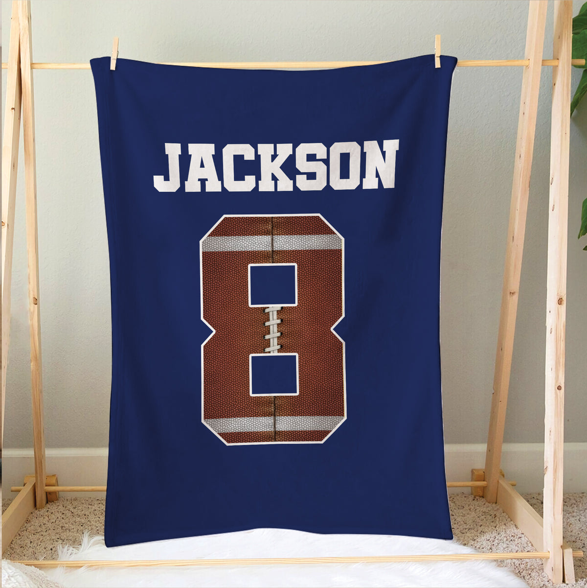 Football blanket hanging above a bed with bold varsity-style sports artwork