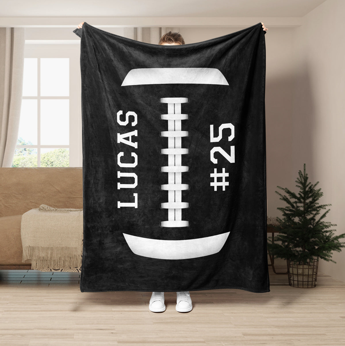 Black football throw blanket held indoors with bold white football graphics and laces