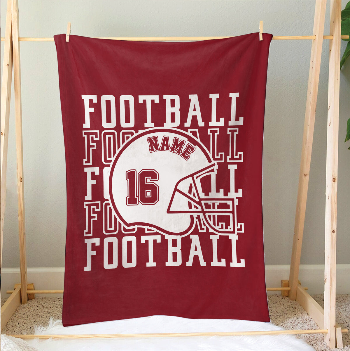 Red football blanket hanging on a wooden display frame with helmet design