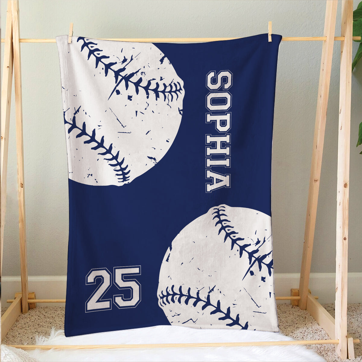 Navy softball blanket hanging on a wooden frame with oversized stitched ball artwork