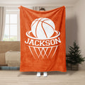 Orange basketball throw blanket displayed in a bright living room with basketball hoop design