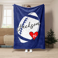 Blue football throw blanket with bold white football artwork and red heart accent in a living room