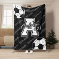 Black soccer blanket featuring white soccer balls, bold athletic graphics, and a monochrome team design