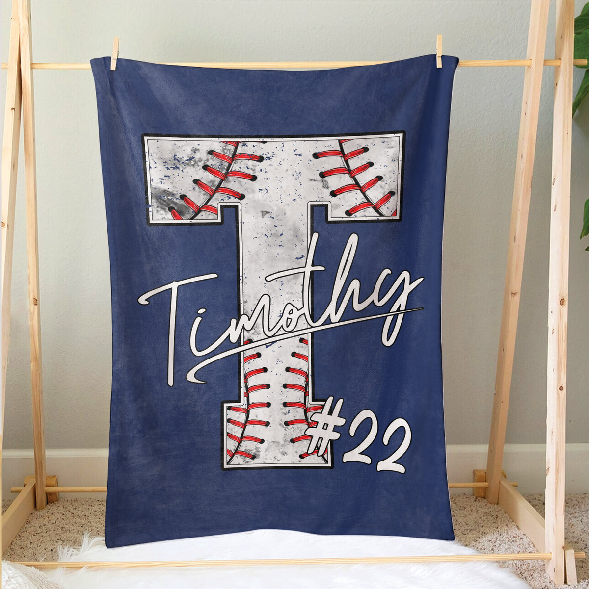 Navy baseball blanket hanging as bedroom decor with a large stitched baseball design