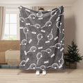Gray tennis blanket showing a repeating white tennis racket and ball design