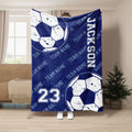 Navy soccer throw blanket displayed in a living room with distressed soccer balls and team-style artwork