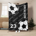Black soccer throw blanket featuring distressed soccer balls and bold monochrome team sports artwork