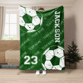 Green soccer throw blanket with distressed soccer balls and repeating team-themed sports artwork