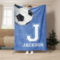 Blue soccer blanket displayed in a living room with an oversized soccer ball and bold athletic letter