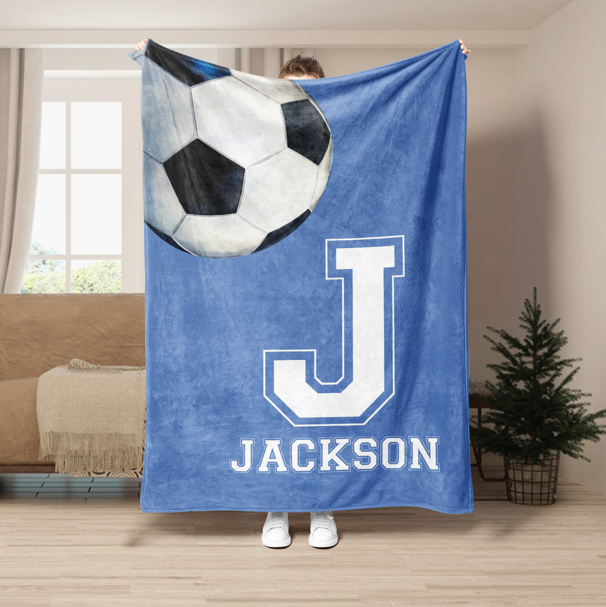 Blue soccer blanket displayed in a living room with an oversized soccer ball and bold athletic letter