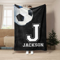 Black soccer throw blanket with oversized soccer ball and bold white athletic letter artwork