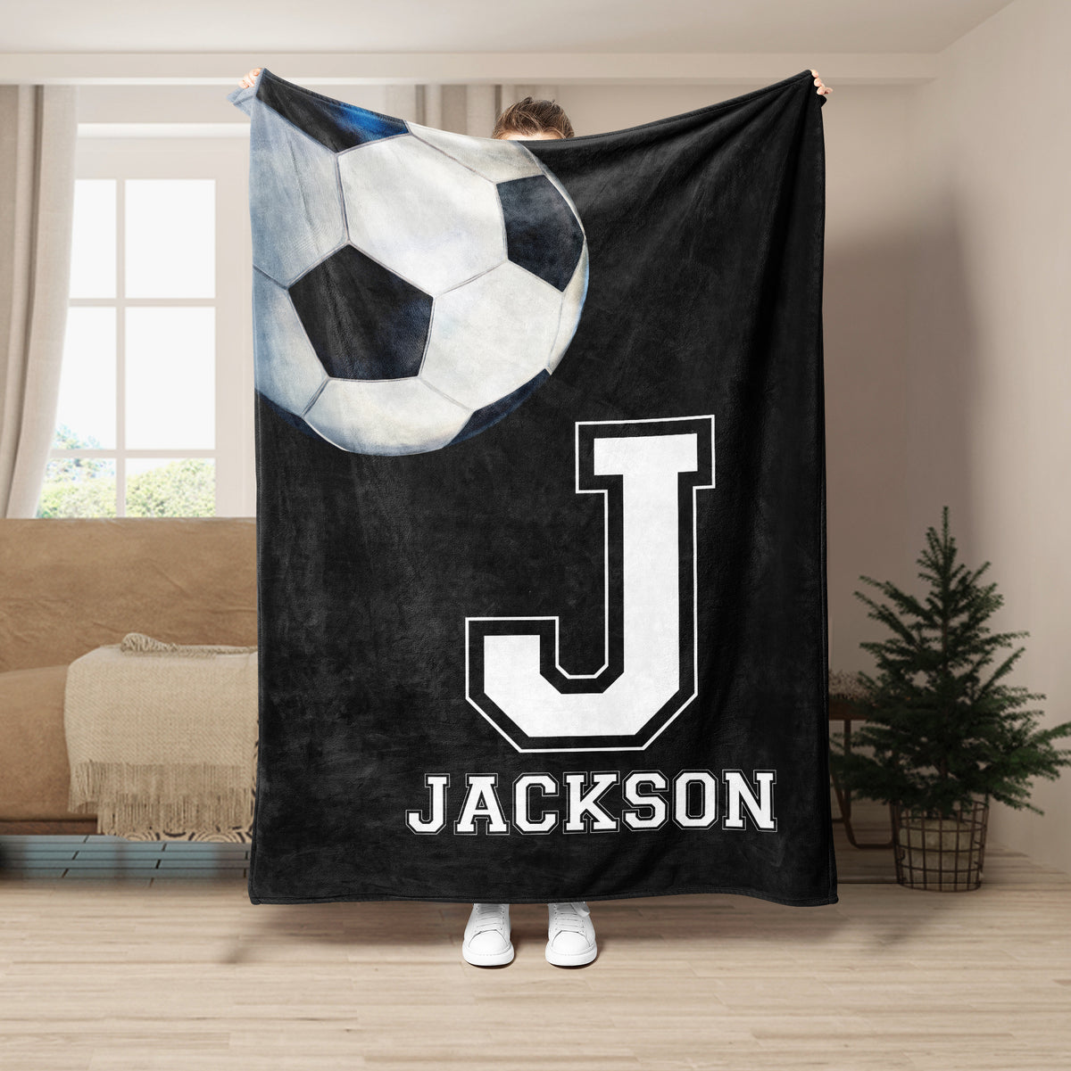 Black soccer throw blanket with oversized soccer ball and bold white athletic letter artwork