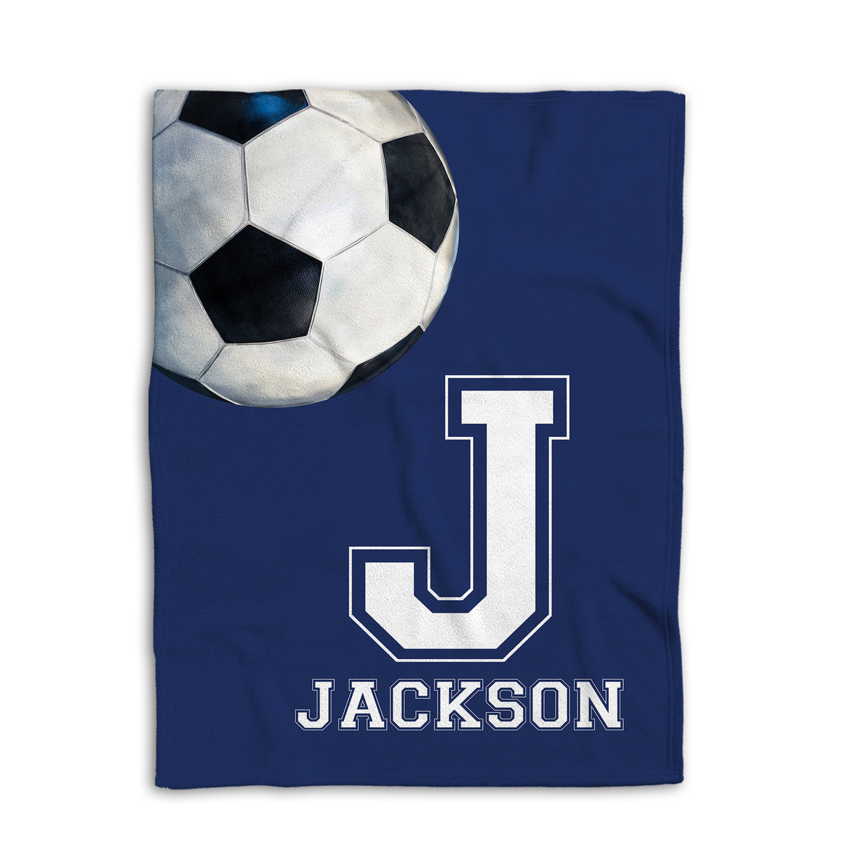 Flat-lay soccer blanket showing an oversized soccer ball and bold athletic letter on a navy background