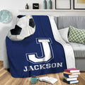 Soccer blanket draped over a sofa with oversized ball artwork and bold athletic letter design