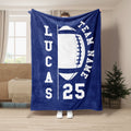 Navy football blanket held up indoors with a large white football graphic and bold athletic design