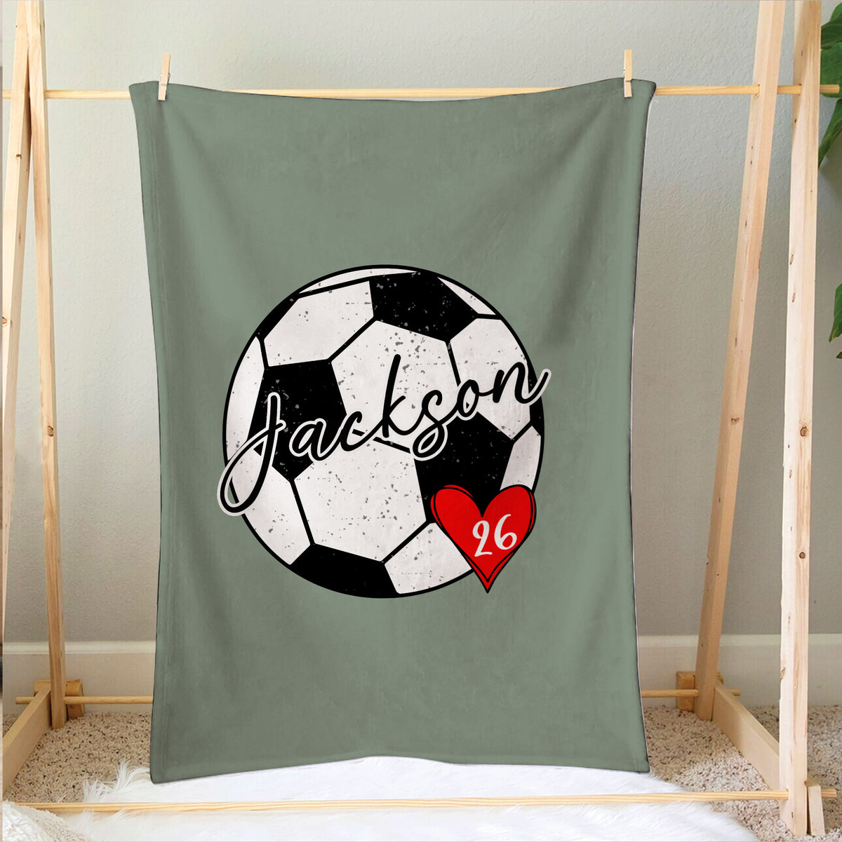 Soccer blanket draped on a bedroom frame with a large black and white soccer ball design