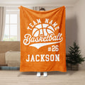 Orange basketball throw blanket displayed in a living room with bold white basketball artwork