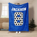 Blue soccer throw blanket shown full length with black and white soccer ball design