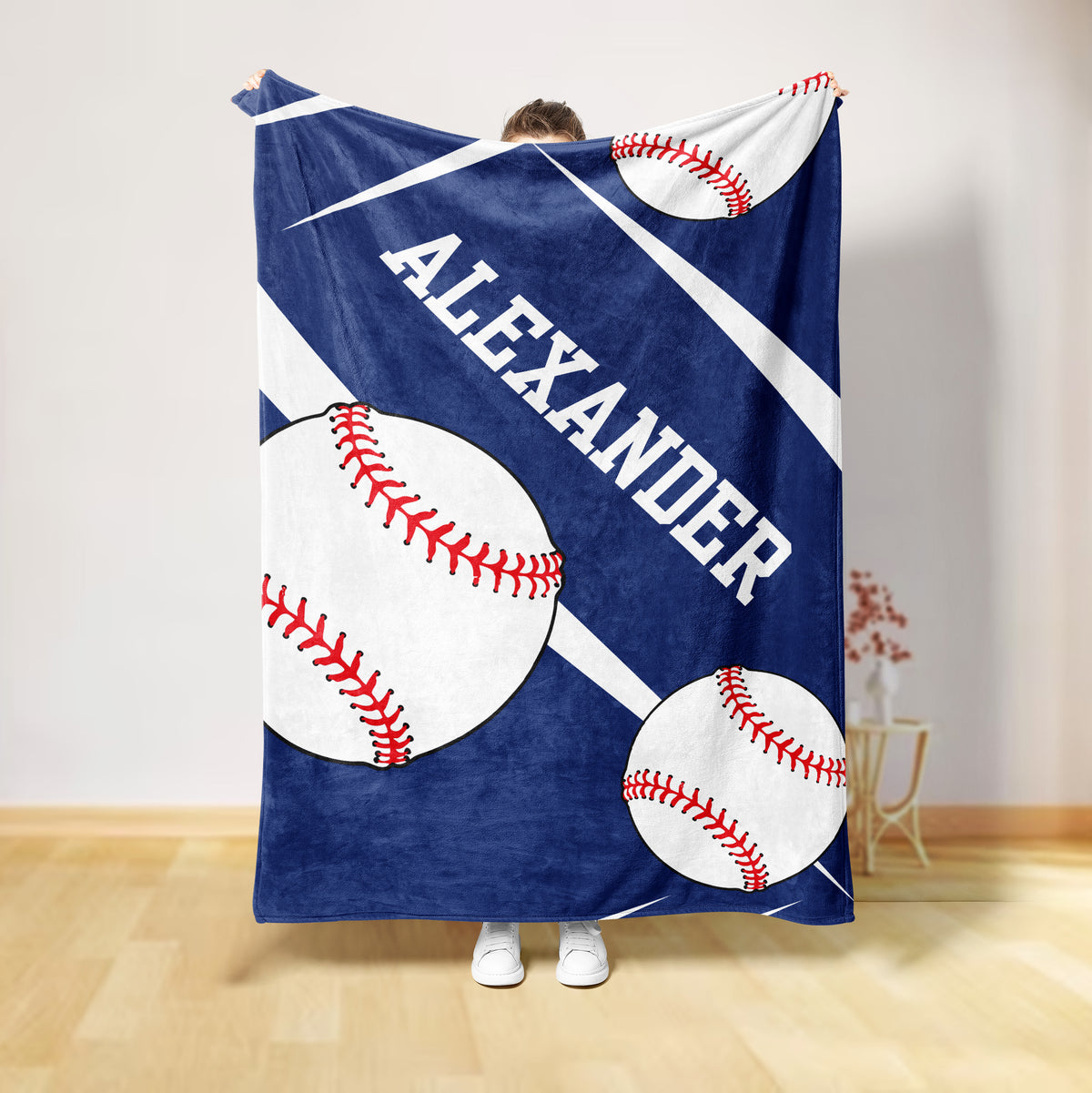 Blue baseball throw blanket shown hanging with oversized white baseballs and red stitching