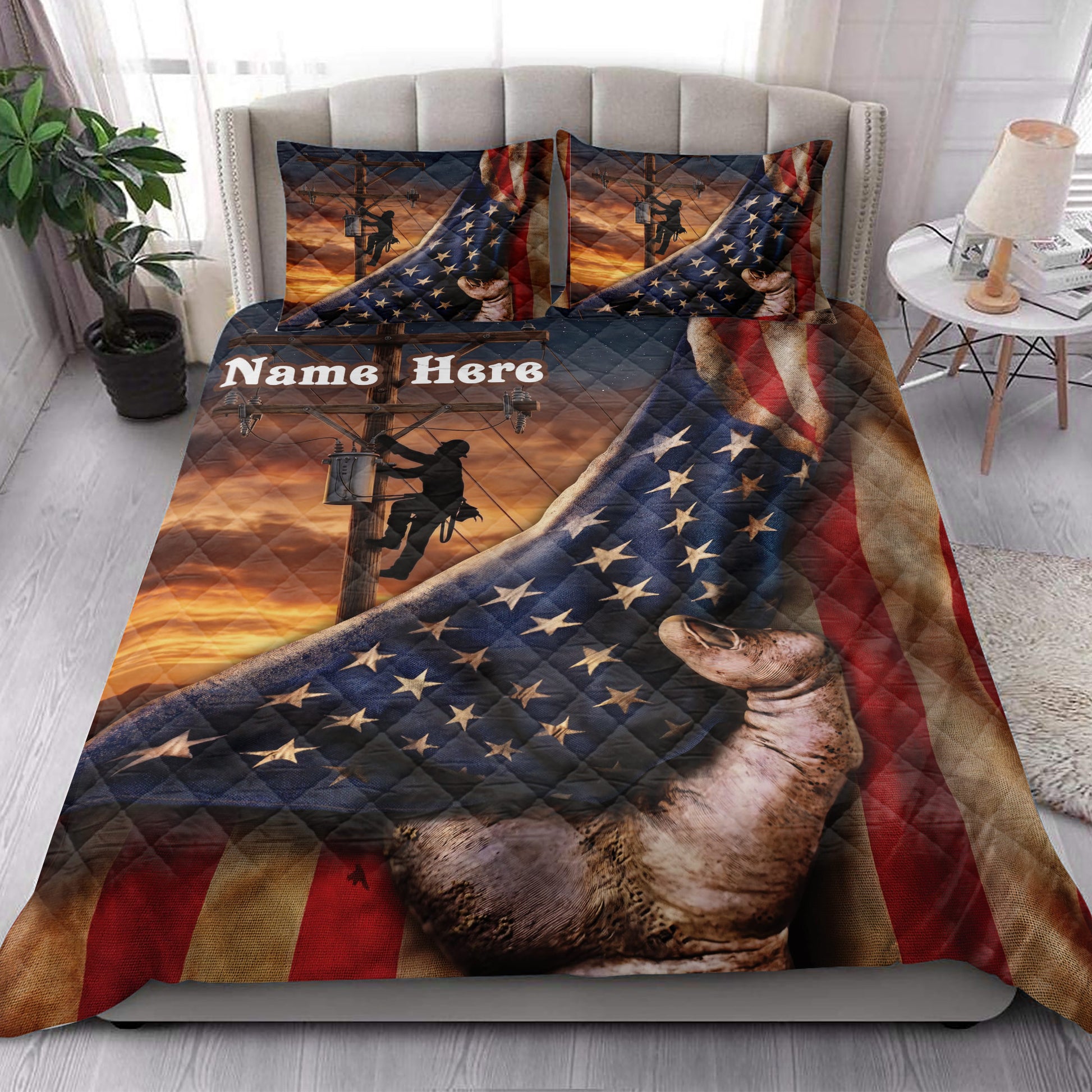 Lineman quilt blanket styled on a bedroom bed with utility pole artwork, stars, stripes, and warm sunset tones