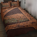Camping quilt blanket displayed on a bed with an RV, mountains, trees, compass, and outdoor gear artwork