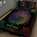 Close view of a black quilt blanket with large multicolor sunflower and decorative feather artwork