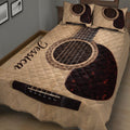 Close view of acoustic guitar artwork across a quilt blanket and coordinating bedding