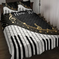 Black and white piano key quilt blanket with gold musical notes styled on a bedroom bed