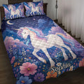 Unicorn quilt blanket displayed on a bed with rainbow-maned unicorns, flowers, stars, clouds, and a crescent moon