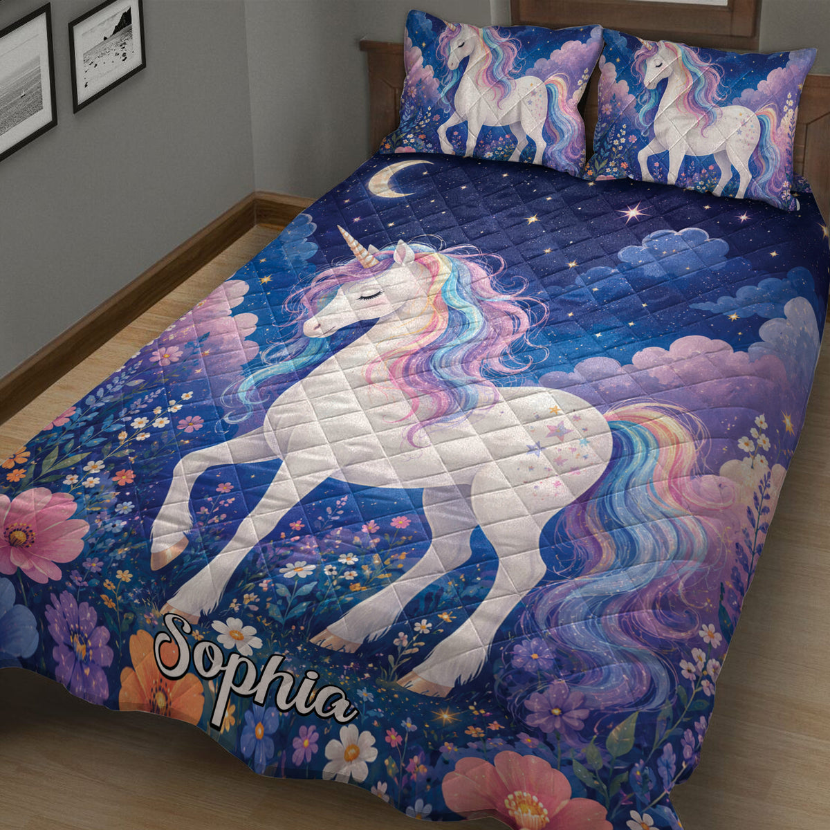 Close bedroom view of a unicorn quilt blanket with rainbow manes, crescent moon, stars, clouds, and flower details