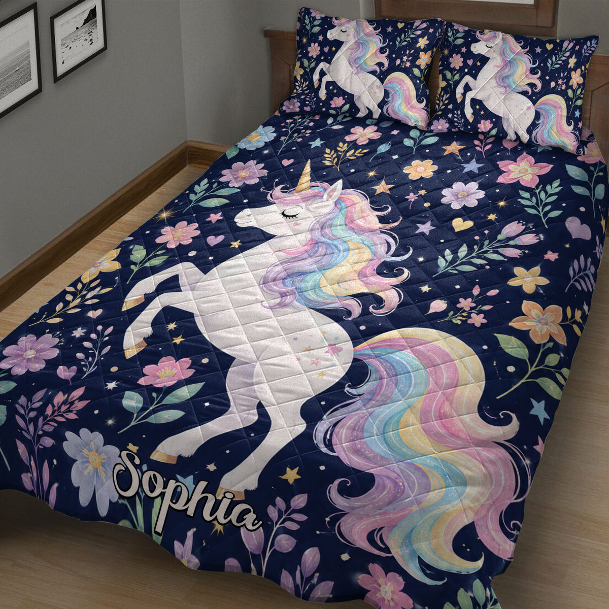 Close bedroom view of a navy unicorn quilt blanket with pastel flowers, stars, and rainbow mane artwork