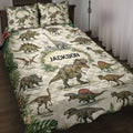 Dinosaur quilt bedding set displayed on a bed with tropical leaves and illustrated prehistoric animals