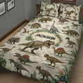 Close bedroom view of dinosaur quilt bedding with illustrated dinosaurs, jungle leaves, and floral accents