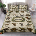 Dinosaur quilt blanket styled on a bedroom bed with realistic dinosaurs, jungle foliage, and neutral vintage-inspired artwork