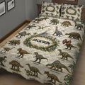 Close bedroom view of a dinosaur quilt blanket featuring realistic T-rex, triceratops, stegosaurus, and other prehistoric animals