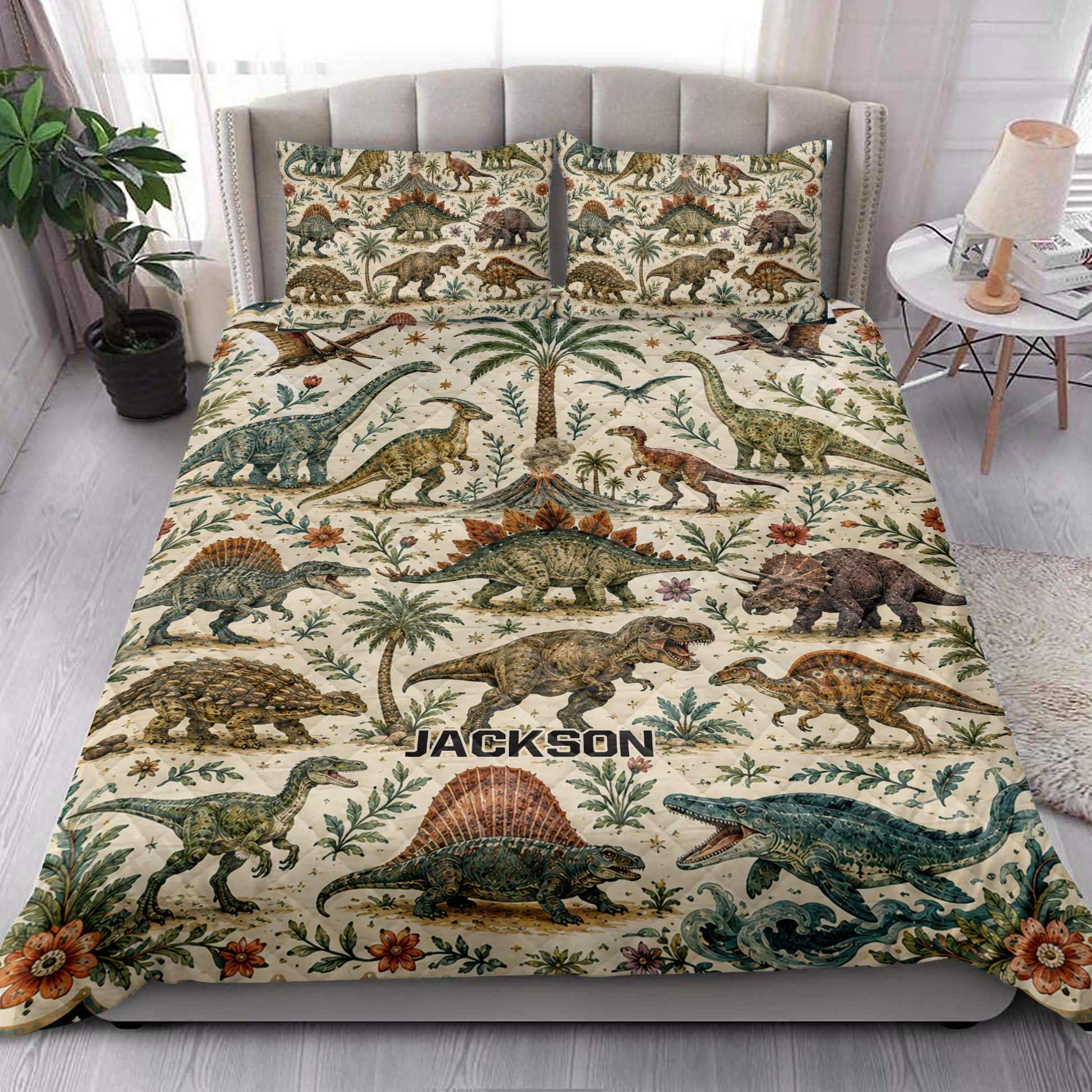 Dinosaur quilt bedding styled in a bright bedroom with colorful prehistoric animals, plants, flowers, and volcano artwork