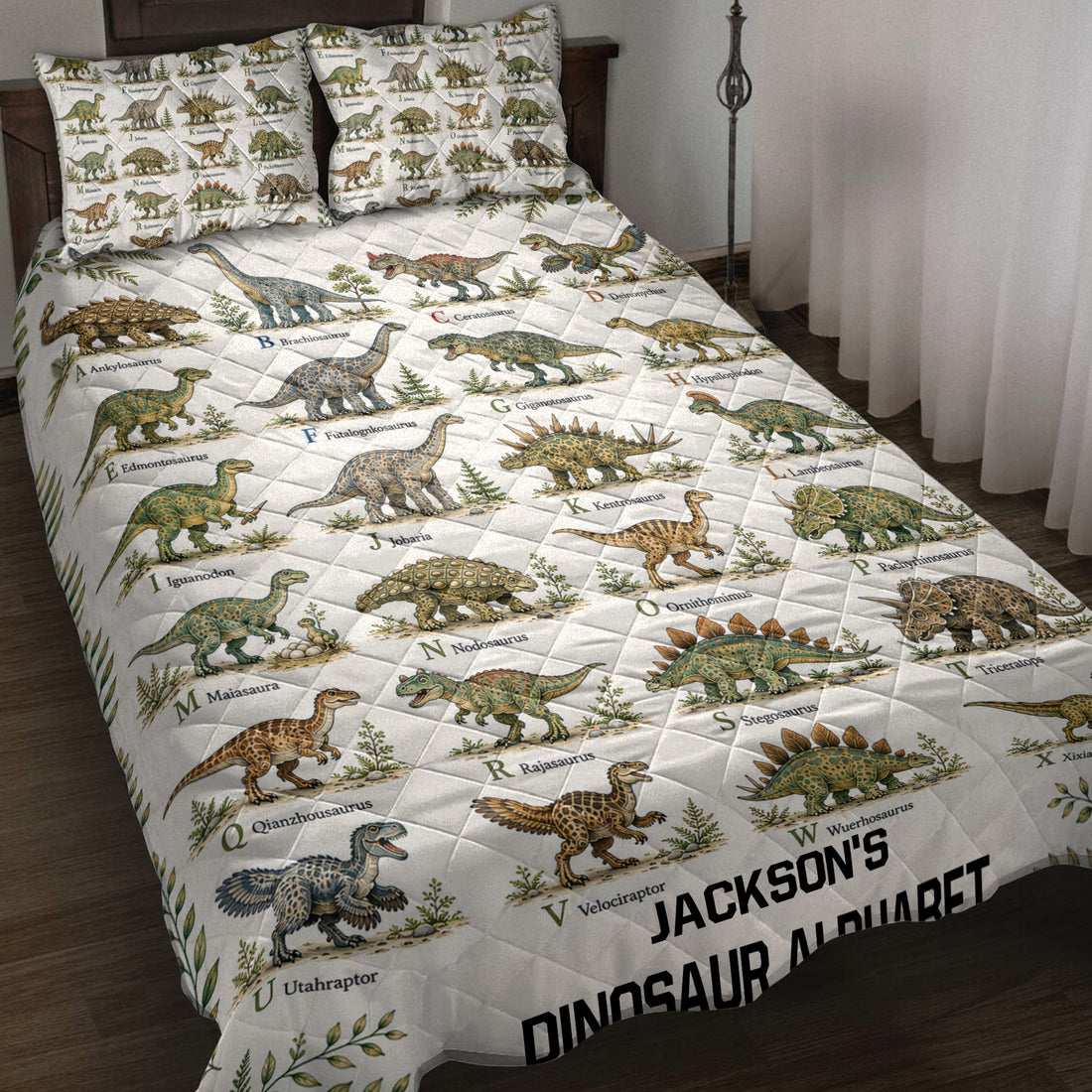 Dinosaur alphabet quilt blanket spread across a bed with illustrated prehistoric animals and leafy accents