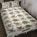Dinosaur alphabet quilt blanket spread across a bed with illustrated prehistoric animals and leafy accents