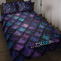 Dragon-inspired quilt blanket with layered purple, blue, and teal scales styled on a bedroom bed