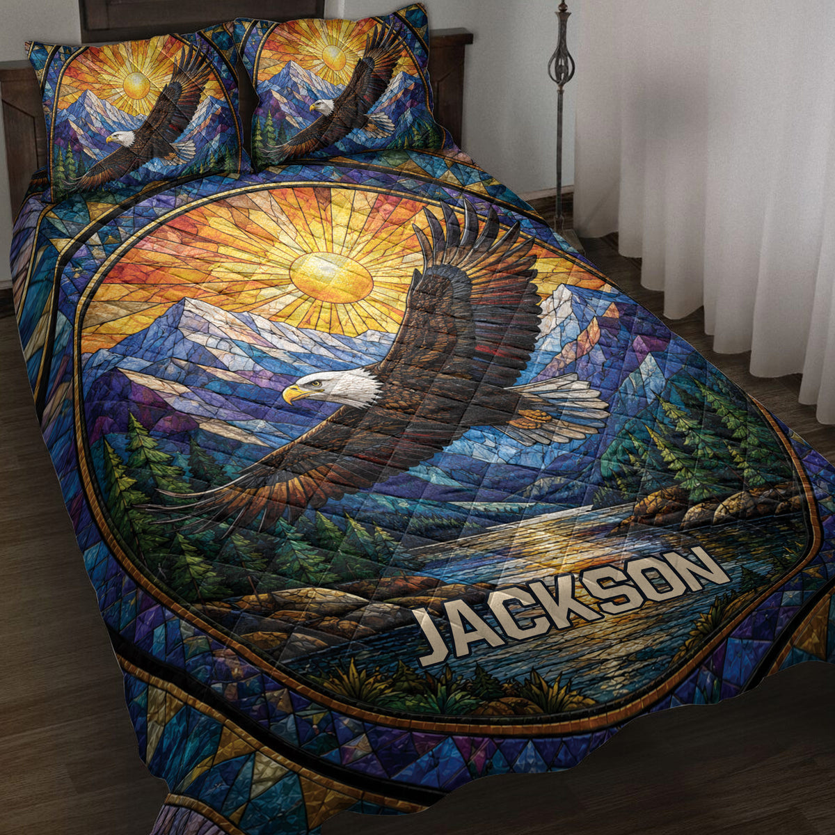 Eagle quilt blanket displayed on a bed with stained-glass mountain, forest, and sunrise artwork